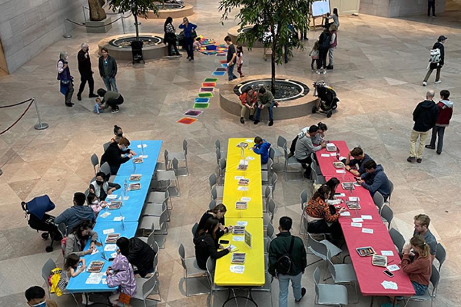 Groups of people sitting a multiple tables making arts and crafts.