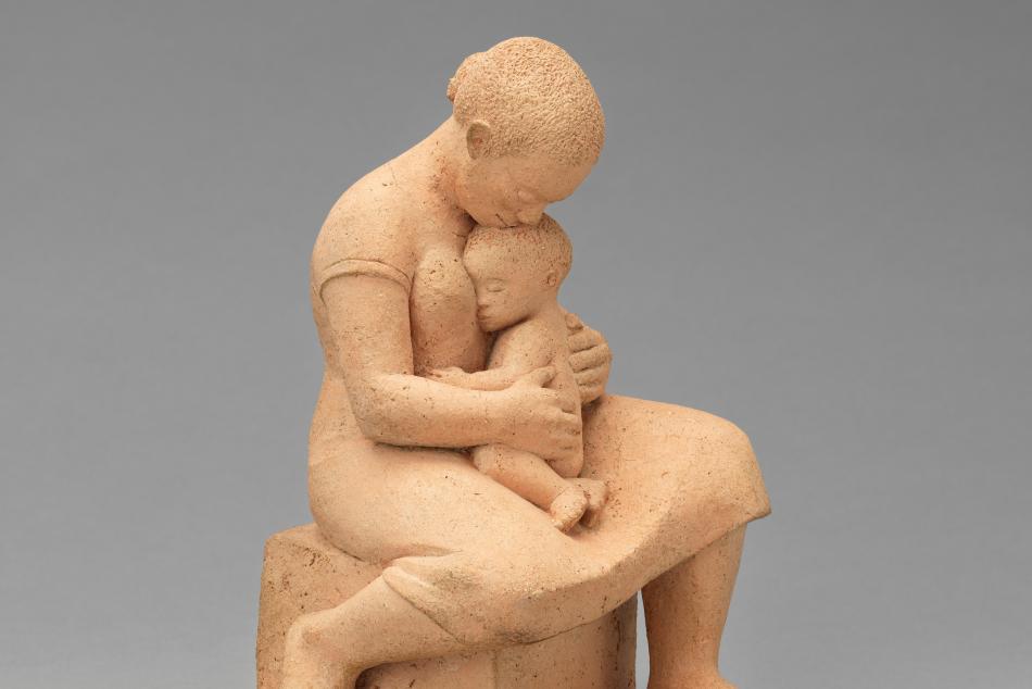 A sculpture of a woman holding a small child in her lap.