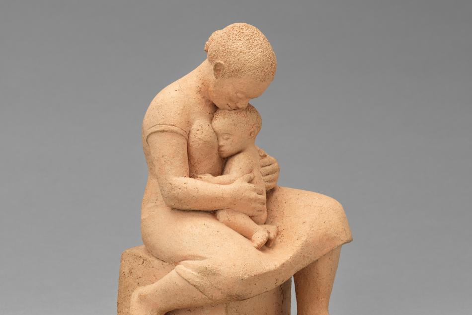 A sculpture of a woman holding a small child in her lap.