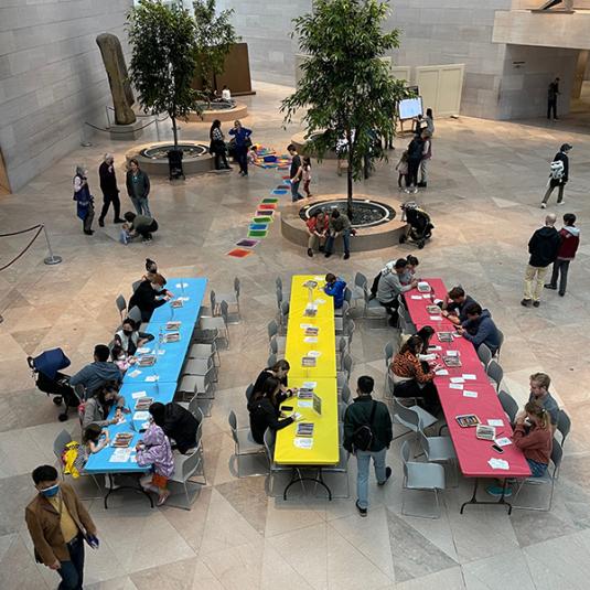 Groups of people sitting a multiple tables making arts and crafts.