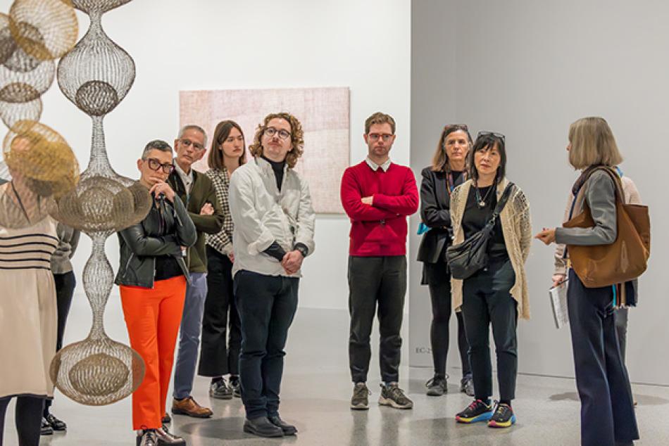 A group of fellows take a tour of Ruth Asawa's hanging sculptures